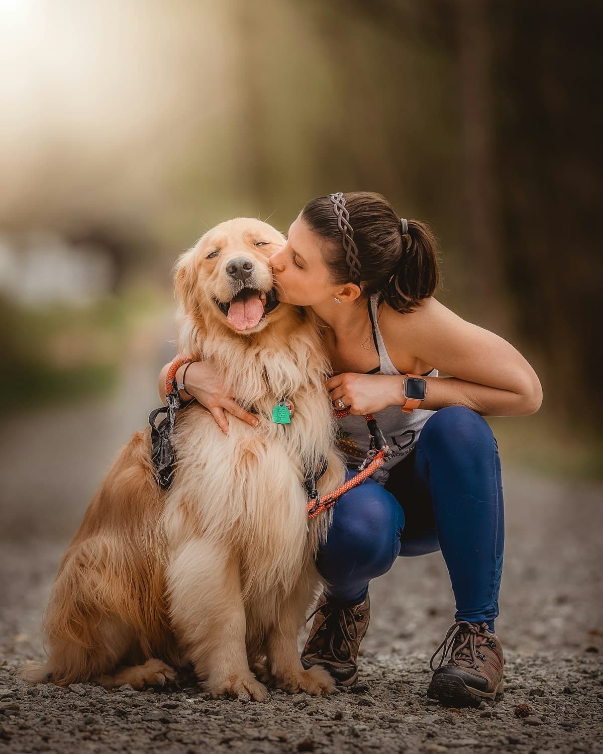 A woman kissing her golden retriever on the head outdoors